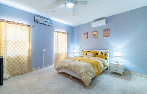 Guest bedroom with pale blue walls, gold bedding and a ceiling fan