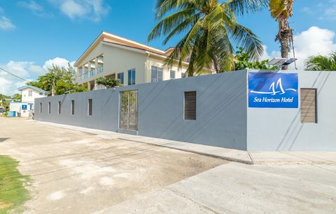 The blue Sea Horizon Hotel sign on the pale grey perimeter wall, with palms overhead