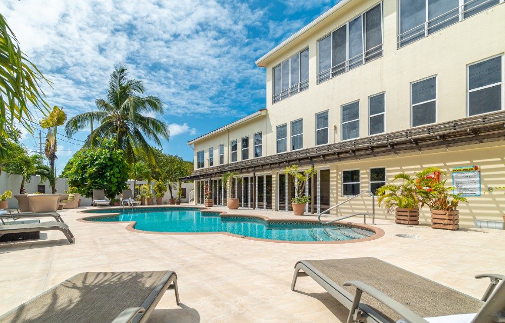 Sun loungers on the tiled deck beside the Sea Horizon pool, with the hotel building and palms behind