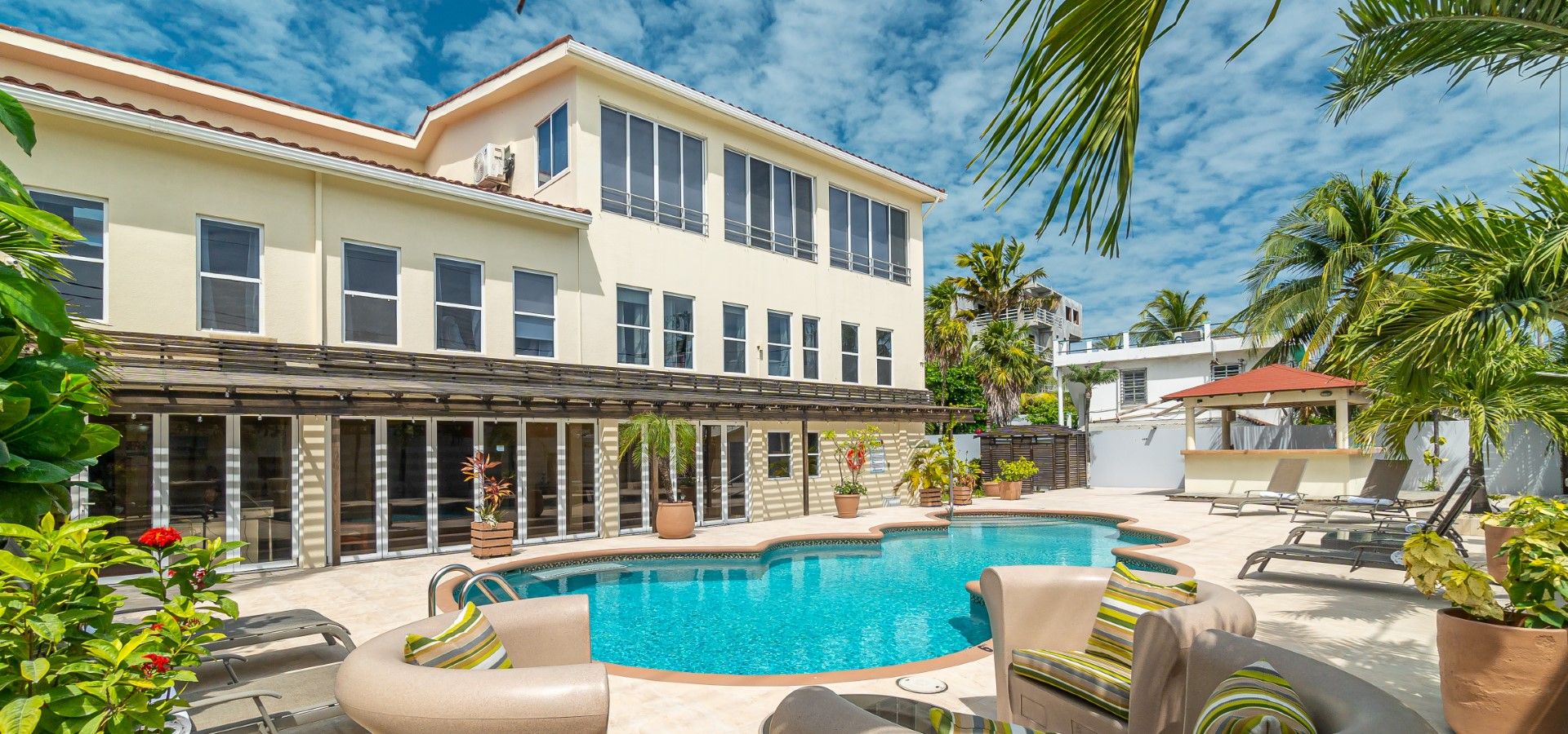 The Sea Horizon Hotel building with its outdoor pool, sun deck and palm trees under a blue Belizean sky