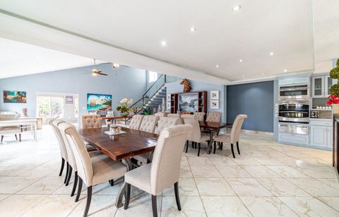 Long dining table with upholstered chairs and the kitchen behind it
