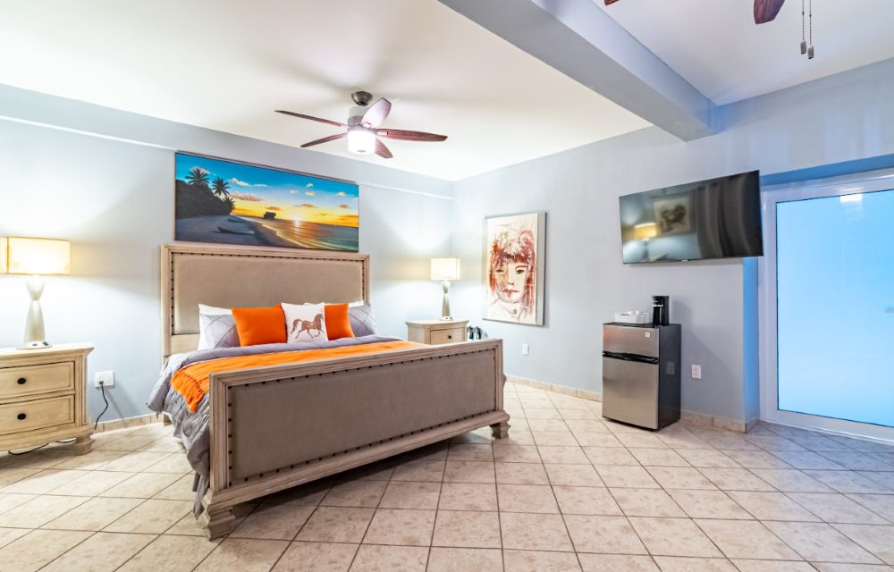 Luxury Room at Sea Horizon with a king-size bed, orange accent cushions, a chest of drawers and framed artwork