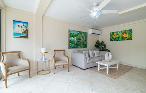 Sitting area with armchairs, a sofa and tropical paintings on the wall