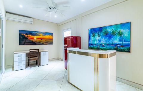 The reception counter, with a desk, a red refrigerator and framed island paintings behind it