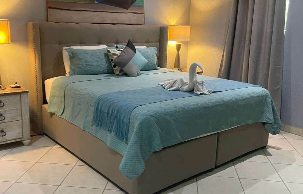 Deluxe Room at Sea Horizon with a king-size bed, sea-green bedding and a tall upholstered headboard