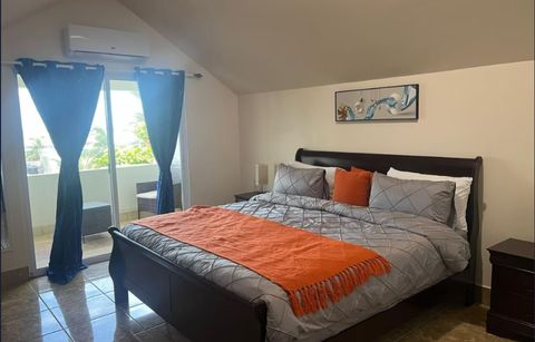 Deluxe Penthouse bedroom with a dark wood king bed and balcony doors framed by blue curtains