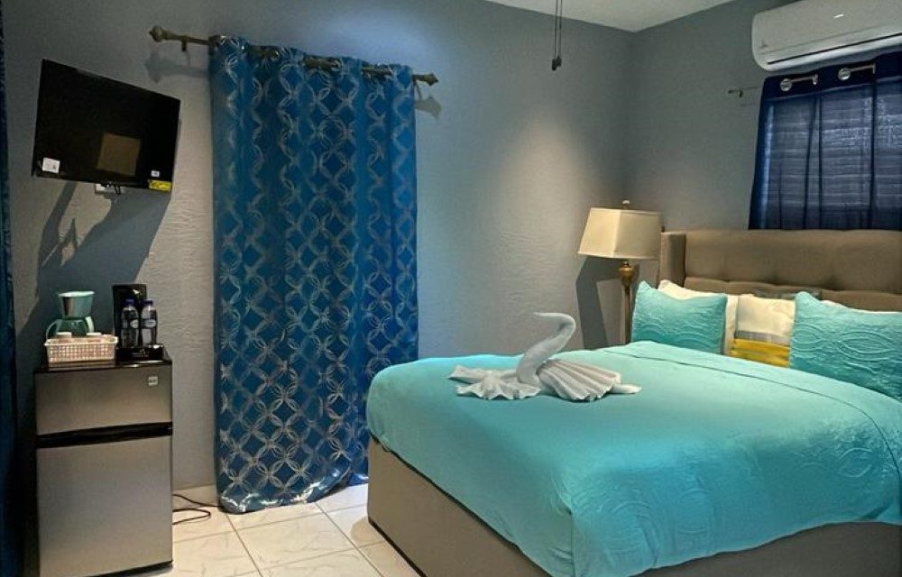 Boutique Room at Sea Horizon with turquoise bedding, a wall-mounted television and a blue patterned curtain